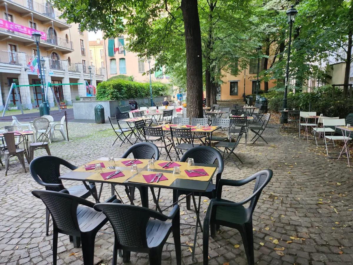 The outdoor area: set tables on the cobblestones, under the trees